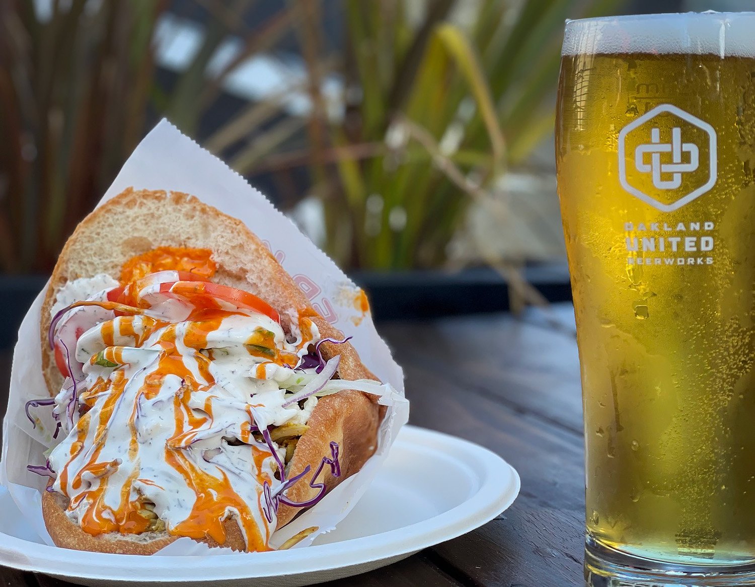 A donor kebab on a white plate next to a full glass of beer.