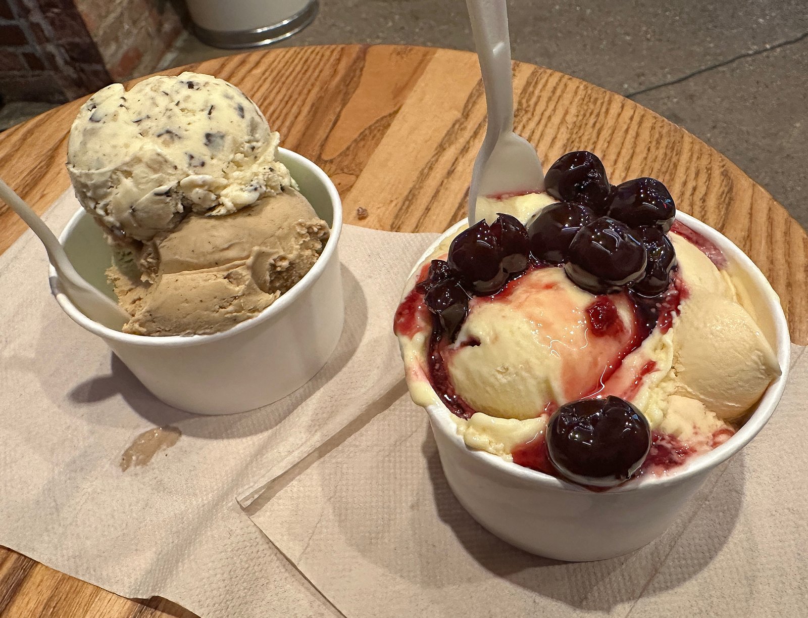 two cups of ice cream with cherries and a spoon