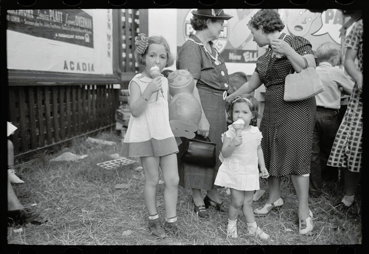 Two young girls are eating ice cream cones.